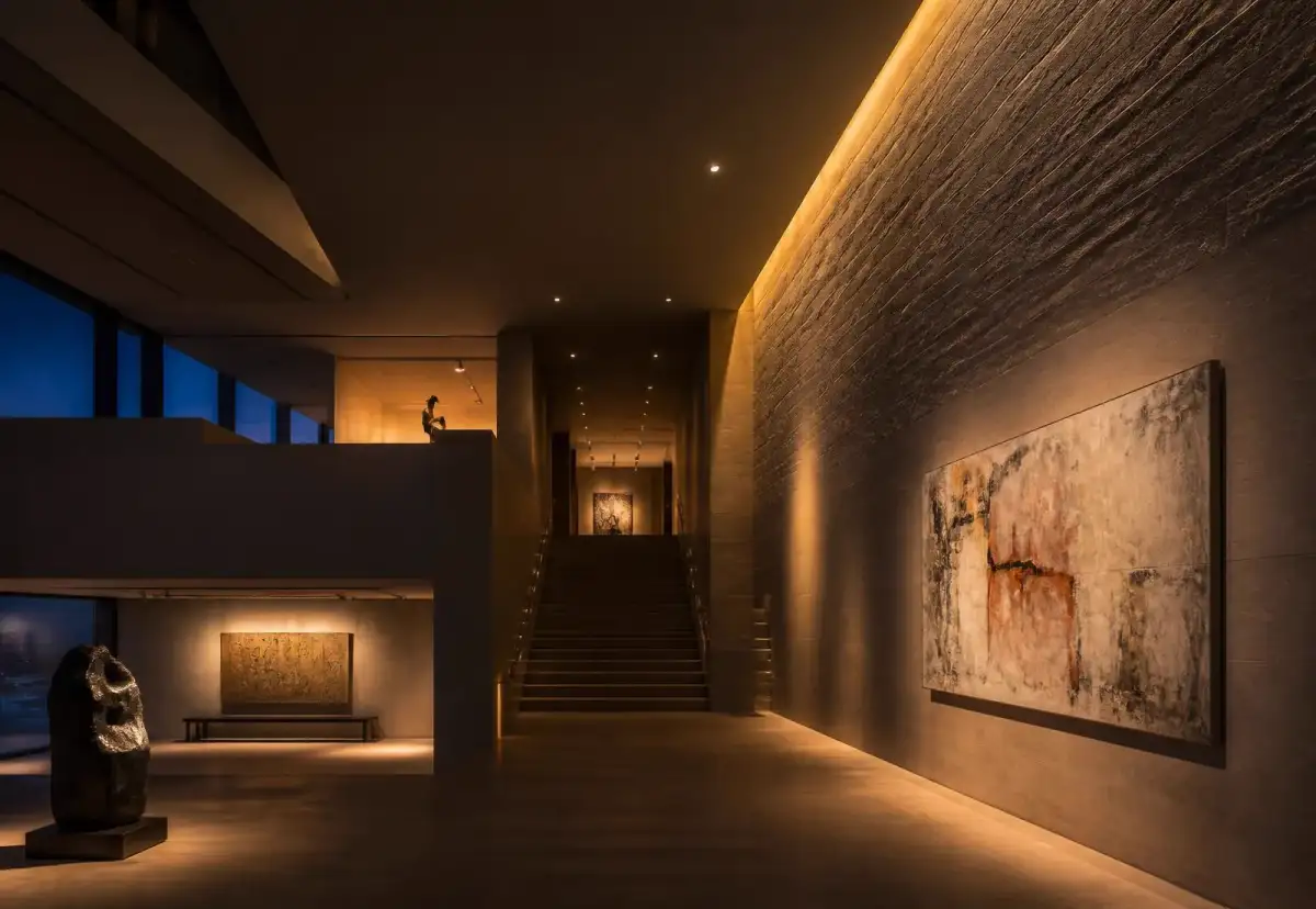Interior at dusk with cove lighting and accent spotlights grazing a stone wall